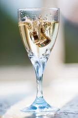 Wedding rings fall in glass with champagne