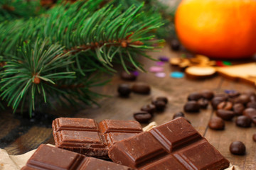 tangerines with chocolate and coffee beans near spruce branches on wooden background