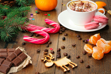 tangerines and fir-tree branches cone and Christmas candy and cookies and a Cup of coffee on wooden background