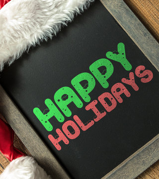 Happy Holidays written on blackboard with santa hat