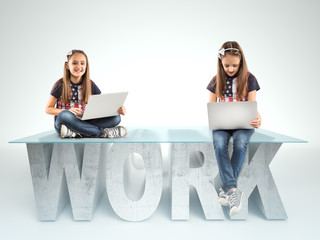 Cute little girls sitting on a WORK table design, and holding a laptop. Bussines concept