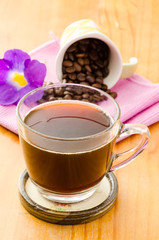 The cup of hot coffee and coffee bean on wooden background