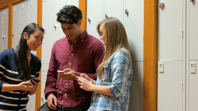 Students using smartphones in locker room