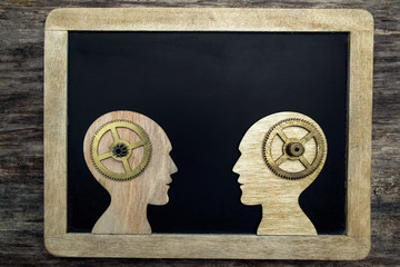 Two human head silhouettes with gears