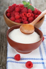 Raspberries in a bowl and sugar.
