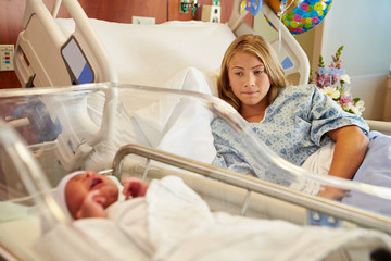 Worried Teenage Girl With Crying Newborn Baby In Hospital