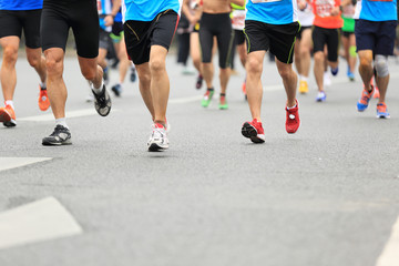 Fototapeta premium Unidentified marathon athletes legs running on city road