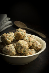 Bayrische Semmelknödel vegetarisch in einer Schüssel auf Holztisch mit Holzlöffel und gestapelten Leinenservietten