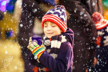 Little kid boy with hot chocolate on Christmas market