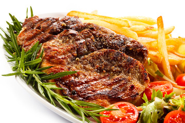 Grilled steak, French fries and vegetables on white background 