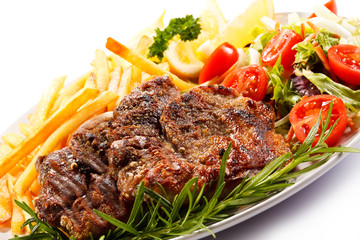 Grilled steak, French fries and vegetables on white background 