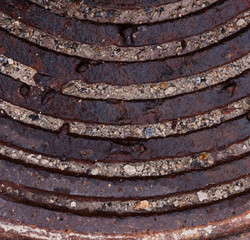 Fragment of an old rusty manhole covered with dirt
