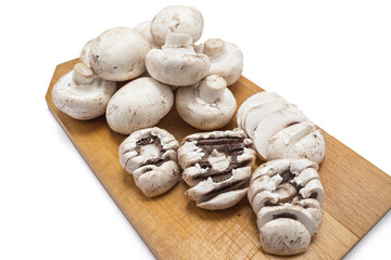 Fresh raw champignons portobello mushrooms on a wooden plate isolated on white background