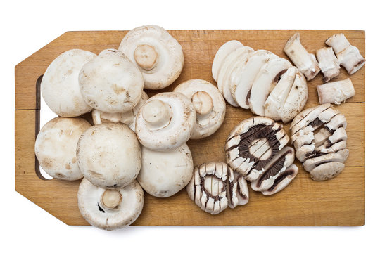 Fresh raw champignons portobello mushrooms on a wooden plate isolated on white background