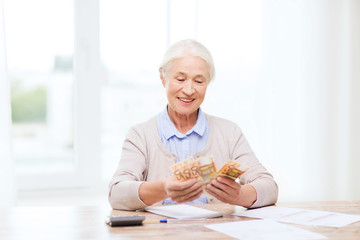 senior woman with money and papers at home