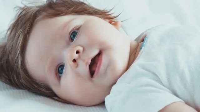 Closeup portrait of blue-eyed newborn baby girl boy lying on the bed