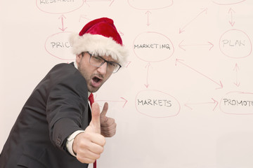 Businessman with Santa hat expressing satisfaction showing his thumbs up   