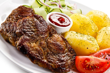 Grilled steaks, boiled potatoes and vegetable salad 