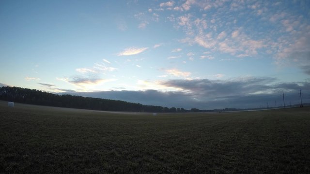 Time lapse of the sunset with storm clouds on the horizon and fog on the field with compressed crop