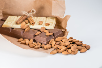 Close-up of still life: white and dark chocolate, almonds, cinnamon, cocoa. shallow DOF