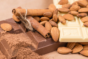 Close-up of still life: white and dark chocolate, almonds, cinna