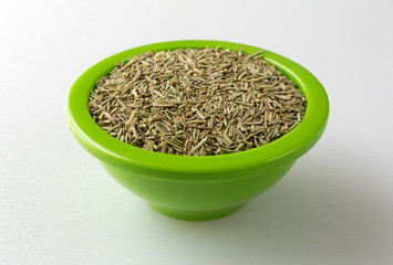 Bowl of rosemary leaves on a cutting board