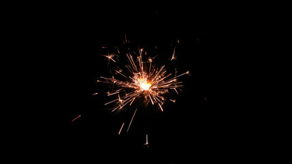 Centrally positioned firework sparkler burning isolated. Gun powder sparks shot against deep dark background