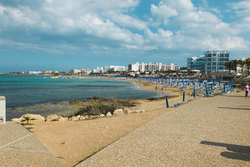Obraz premium Colorful beach on which people are sunbathing with white buildings on a background