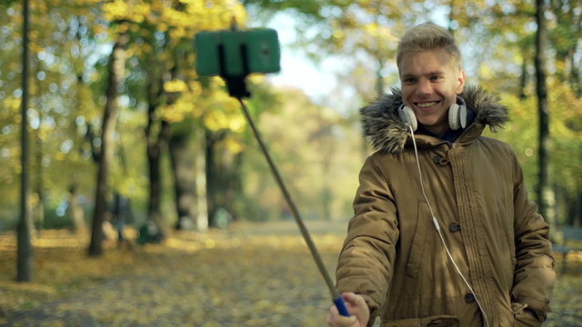 Man using selfiestick and doing photo on smartphone in the park
