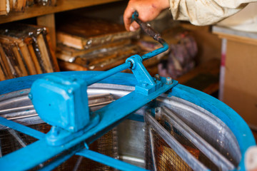Beekeeper harvesting raw honey from bee hives with special blue arrangement
