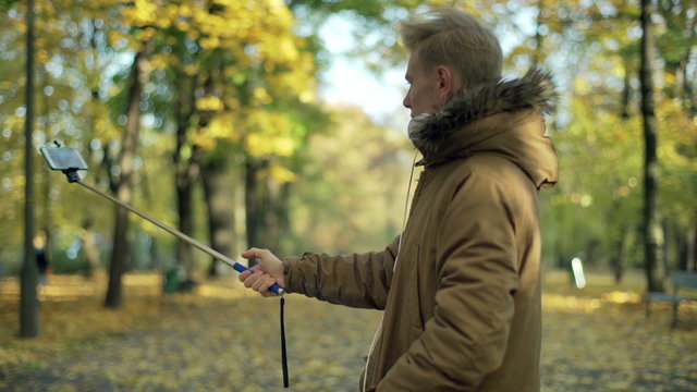 Man using selfiestick and recording on smartphone in the park
