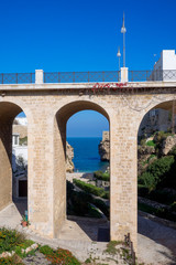 Fototapeta na wymiar Stone bridge with a view of the sea on the background. Polignano a Mare - Apulia, Italy