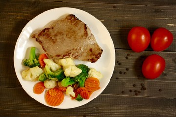 steak with vegetables on a wooden background