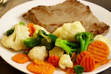 steak with vegetables on a wooden background