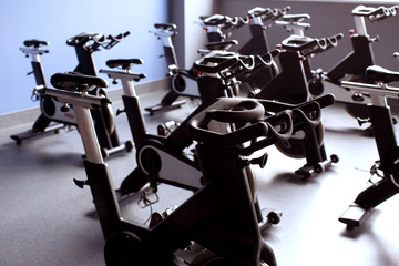 A row of black exercise bikes in a bright large gym room