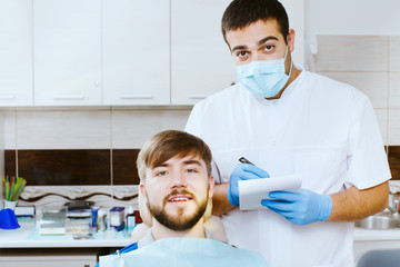 dentist taking notes with patient, at the dental office.