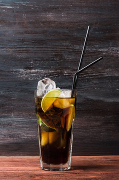 Glass of cola with ice and lime on the rustic background