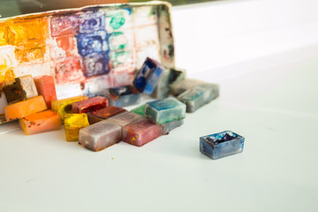 Акварель в маленьких коробочках, рассыпанных по столу