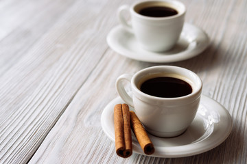Two cups of espresso on a white wooden table