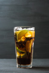 Glass of cola with ice and lime on the rustic background