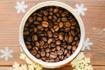 Coffee beans in tin on a wooden table with decorations