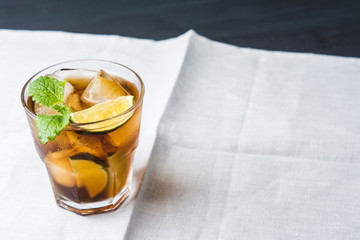 Cuba libre with lime on black wooden table