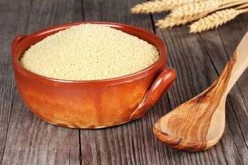 couscous in an earthenware bowl and wooden spoon