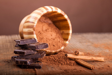 broken dark chocolate and cinnamon stick on wooden background