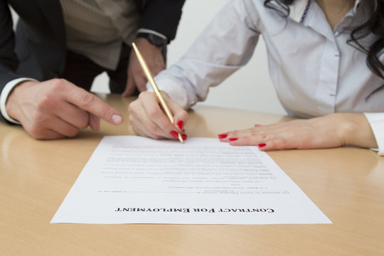 Employer showing new employee where to sign employment contract