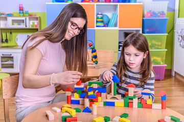 Preschool Teacher And Cute Girl Building Toy Blocks Castle