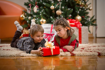 Fototapeta na wymiar Cute little children opening Christmas presents