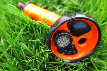 Adjustable shower (spray) lying on the fresh lawn grass in the summer garden