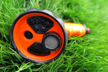 Adjustable shower (spray) lying on the fresh lawn grass in the summer garden