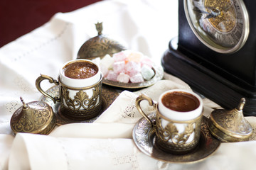 Turkish coffee with delight and traditional copper serving set, vintage clock